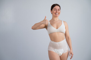 Woman in adult diapers smiling and showing thumbs up. Urinary incontinence problem.  - obrazy, fototapety, plakaty