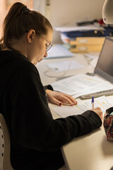 Blur effect. Young blonde girl, studying at home with a computer and typing. 