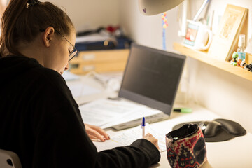 Blur effect. Young blonde girl, studying at home with a computer and typing. 