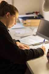 Blur effect. Young blonde girl, studying at home with a computer and typing. 