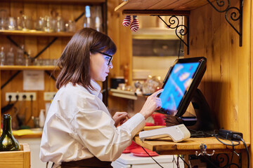 Female restaurant worker using computer terminal while serving customers - obrazy, fototapety, plakaty