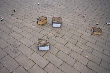 Tattered fireworks and the remains of fireworks  lie on the sidewalk.