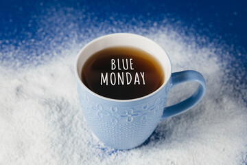 Cup of tea with snow on a blue background with "Blue Monday" lettering. The saddest day of the year. Blue monday creative concept.