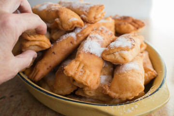 Woman hand approaching a bowl with casadiellas. Traditional christmas dessert in Asturias