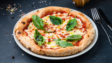 Italian pizza Margarita with mozzarella, tomato sauce, basil on a thick dough with spices.