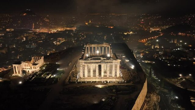 Aerial drone night video of iconic illuminated landmark Acropolis hill and the Masterpiece of Ancient times and Western civilisation - the Parthenon, Athens, Attica, Greece