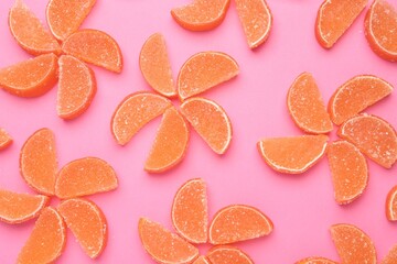 Delicious orange marmalade candies on pink background, flat lay