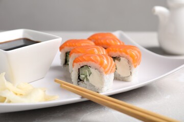 Tasty sushi rolls, soy sauce and ginger on grey table, closeup