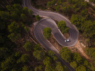 Aerial view of car driving down windy foggy road