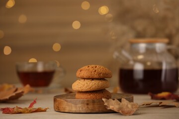 Delicious cookies and autumn leaves on wooden table