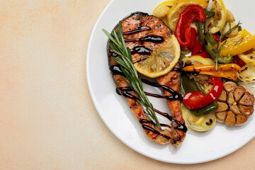 Tasty salmon steak with sauce, lemon and vegetables on light table, top view. Space for text