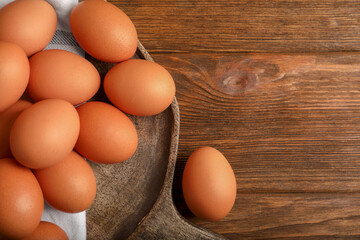 Raw brown chicken eggs on wooden table, flat lay. Space for text
