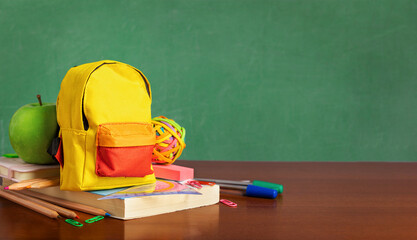 Backpack with a different colorful stationery on the background of the blackboard with copy space © kucherav