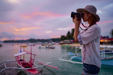 Photography and travel. Young woman in hat holding camera  with beautiful tropical sea view.