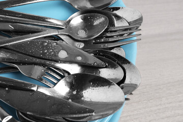 Silver clean spoons, forks and knives on white wooden table, closeup