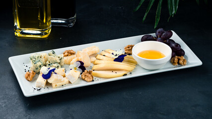 Set to wine fresh cheese plate with dor blue cheese, parmesan, brie, pear, walnuts, grapes and honey.