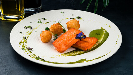 Fried salmon fillet with cheese balls and sauce.