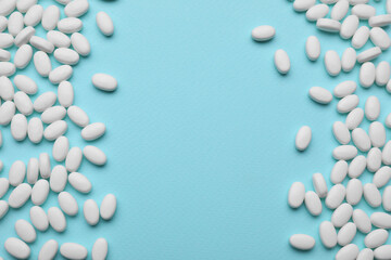 Many dragee candies on light blue background, flat lay. Space for text