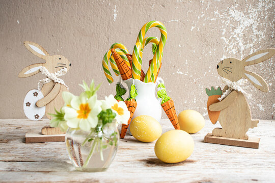 Easter still life. Colored eggs, carrot-shaped sweets, spring flowers.
