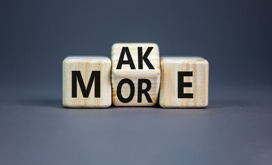 Make more symbol. Concept word Make more on wooden cubes. Beautiful grey table grey background. Business and make more concept. Copy space.