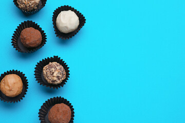 Tasty chocolate candies on light blue background, flat lay. Space for text