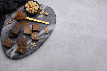 Flat lay composition with tasty chocolate candies and nuts on light grey table. Space for text