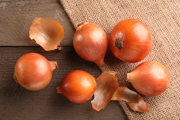 Many ripe onions on wooden table, flat lay