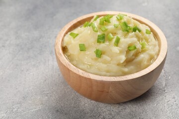 Bowl of tasty mashed potato with greens on grey marble table, closeup. Space for text