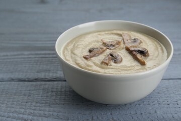 Delicious mushroom cream soup on light grey wooden table. Space for text