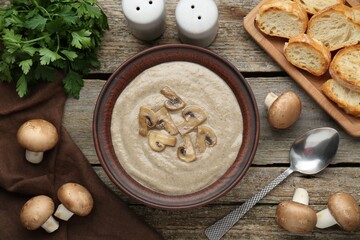 Delicious mushroom cream soup served on wooden table, flat lay