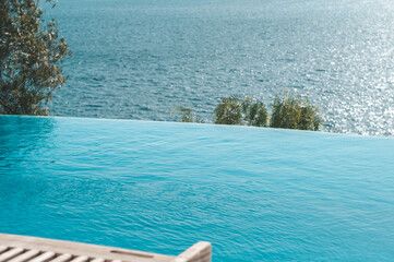 Fototapeta na wymiar Summer vacation at poolside. Infinity swimming pool with sea on bright summer day