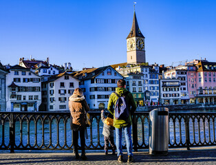 family stands on the sidewalk on the banks of the canal in Zurich - obrazy, fototapety, plakaty