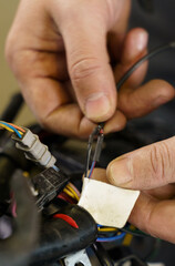 The mechanic sorts out chips for connecting electrical equipment in a motorcycle