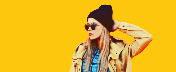 Fashion portrait of blonde young woman in black sunglasses and hat on yellow background