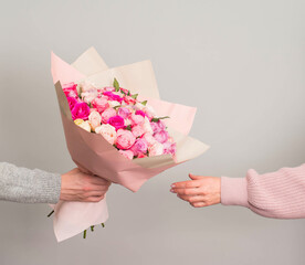 Man hand giving roses flowers bouquet to woman on grey background. Valentines or mothers day...