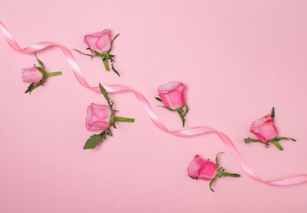 Roses and ribbon on pink background with copy space.