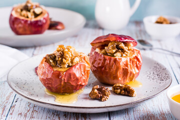 Whole baked apples with honey and walnuts on a plate. Homemade dessert.