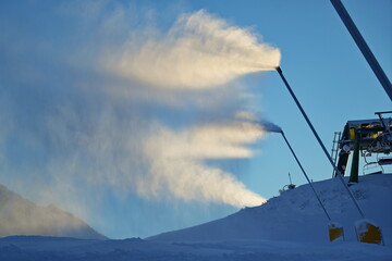 Snow cannon in winter mountains. Snow-gun spraying artificial ice crystals. Machine making snow