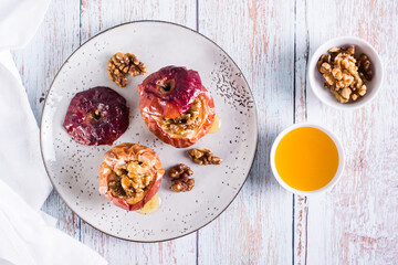 Whole baked apples with honey and walnuts on a plate. Homemade dessert. Top view