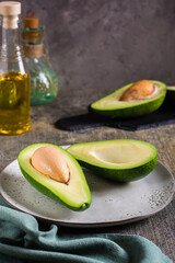 Cut in half fresh avocado on a plate on the table. Healthy food. Vertical view