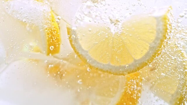 Super Slow Motion Shot of Fizzing Water and Fresh Lemon Slices and Ice at 1000fps. Lemonade Concept
