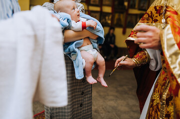 A priest, a Christian in a church conducts a rite, a baptismal ritual with an infant, a child -...