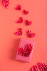 Gift and origami hearts on a red background. Monochrome valentine's day. Vertical view