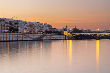 Obraz na płótnie Canvas Sunset over the authentic neighborhood of Tirana in Seville with views on Calle Betis, Torre Sevilla and with awesome reflections in the river Guadalquivir, creating magic atmosphere and views
