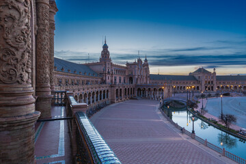 The beautiful decorated Plaza de España (English: Spanish Square) during an colourful sunrise is a touristic spot in a park in the centre of Seville, Spain, built in 1928 for the 1929 world exposition