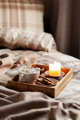 Fototapeta na wymiar warm cozy bedroom winter or autumn concept, cup of hot chocolate on tray, candles throw