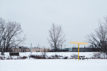 Colorful parasol and bench in lost park urban landscape landfill covered by snow during cold winter in Montreal Quebec