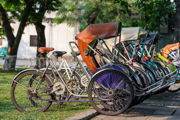 Fototapeta na wymiar Vintage many trishaw stop beside road for service traveller on the street in Vietnam, closeup