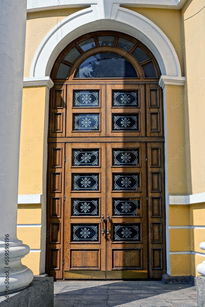 Canvas Prints one big old brown closed wooden door with glass on a white yellow stone wall of a building on a city street