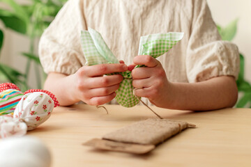 Making Easter decorations. Close-up of a girl's hands making textile easter egg a shape of bunny, rabbit